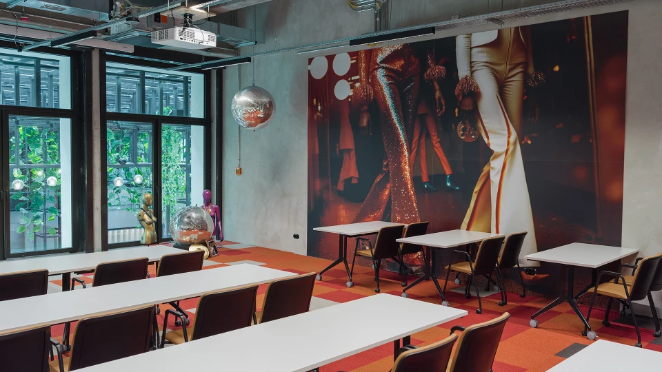 Detailaufnahme der Wandgrafik im Disco Stage mit schimmernden Schlaghosen und Retro-Outfits, im Vordergrund flexible Bestuhlung.