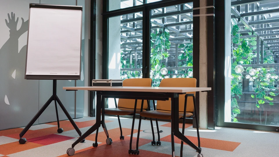 Frontalansicht des Seminarbereichs mit weißen Tischen und beigefarbenen Stühlen, Disco Stage mit markanter Wandgrafik und Diskokugel.