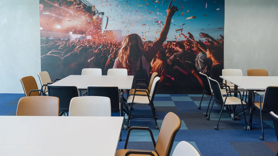 Frontalaufnahme der Elektro Stage mit buntem Konfettimotiv an der Wand und Stuhlkreis.