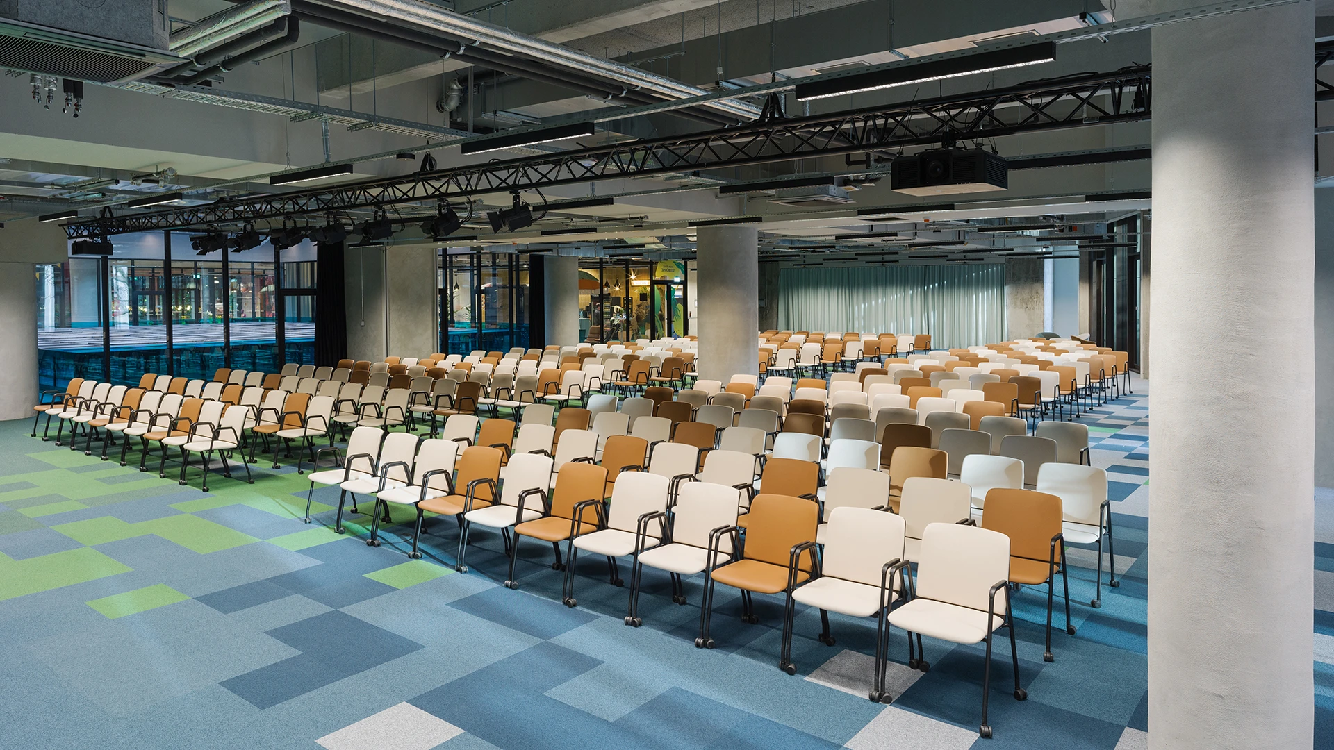 View of a seated event area with a focus on modern ceiling design featuring lighting technology and suspended elements.