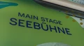"Main Stage Seebühne" sign on an organically designed green wall with dots and shapes in the background.
