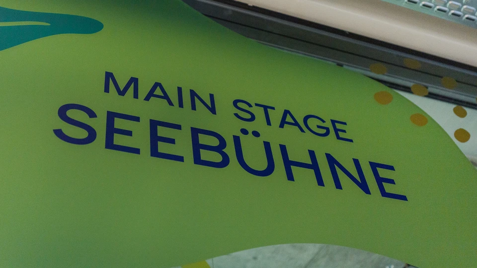 "Main Stage Seebühne" sign on an organically designed green wall with dots and shapes in the background.