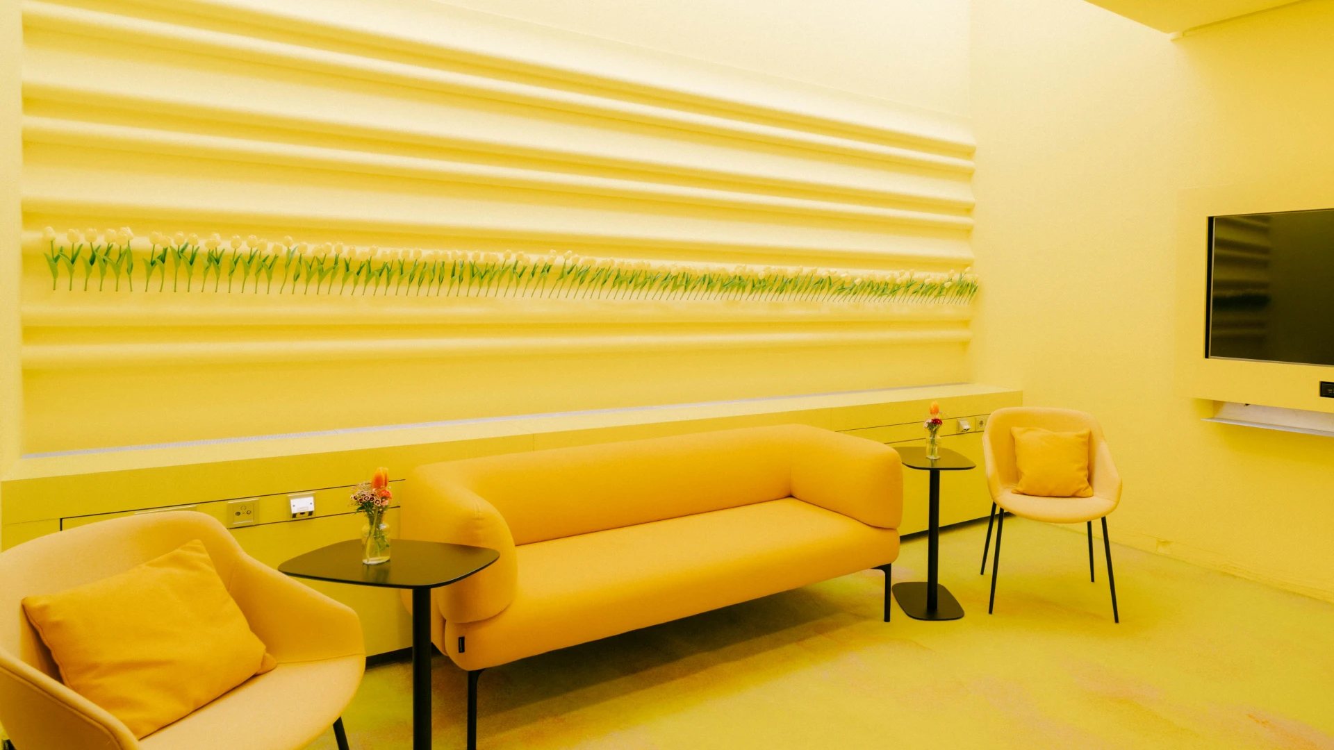 Bright and welcoming conference and meeting room in Smartvillage Bogenhausen, equipped with modern ergonomic chairs, a comfortable yellow sofa, and creative wall decorations.