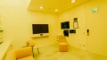 Minimalist meeting room featuring a modern seating arrangement with a yellow designer armchair, a matching footstool, and a wall adorned with vibrant plant pictures – part of the Smartvillage concept