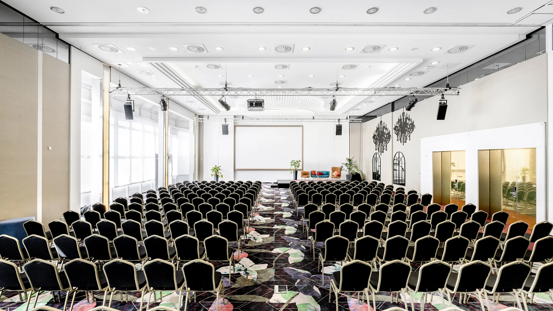 Heller und stilvoller Konferenzsaal mit moderner Bestuhlung, großem Projektionsbildschirm und eleganter Beleuchtung. Perfekt für Tagungen, Präsentationen und Business-Events
