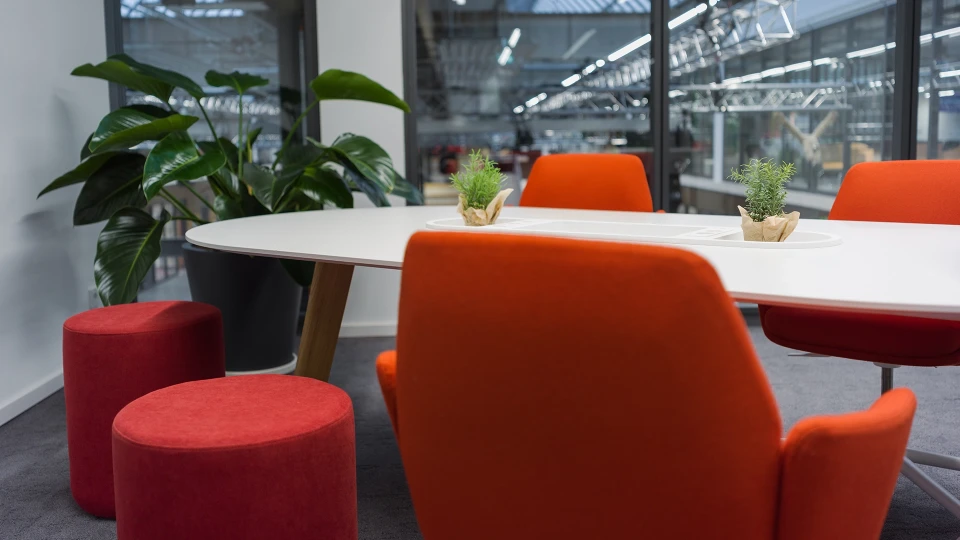 Besprechungsbereich im Smartvillage Köln-Mülheim mit roten Polsterstühlen und Grünpflanze
