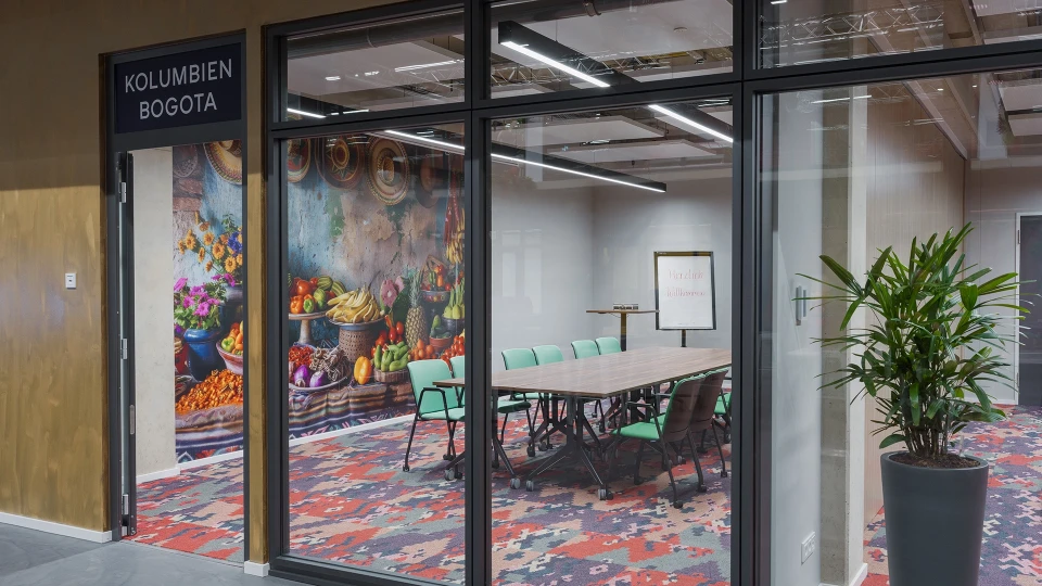 Besprechungsraum Kolumbien Bogota mit Wandbild eines kolumbianischen Marktes und farbenfroher Einrichtung im Smartvillage