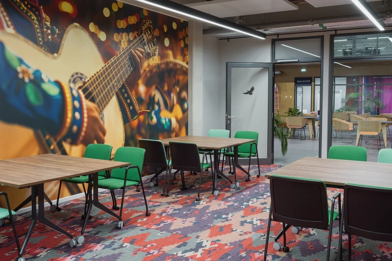 Modern meeting room with tropical plants and a large wall mural of a guitar in the Smartvillage Cologne-Mülheim, room Colombia Cali
