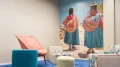 Modernes Wartezimmer mit bunten Stühlen und einem großen Wandbild, das zwei Personen in traditioneller südamerikanischer Kleidung zeigt