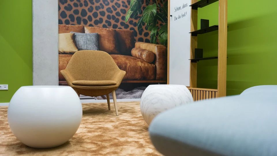 Detailansicht des Raumes "Guyana" mit Sitzmöbeln auf beigem Teppich und Fototapete eines Leopardenmusters samt Couch im Hintergrund.