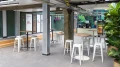 Raum mit Stehtischen und weißen Barhockern im Smartvillage Köln Mülheim Jungle Lodge Bereich.