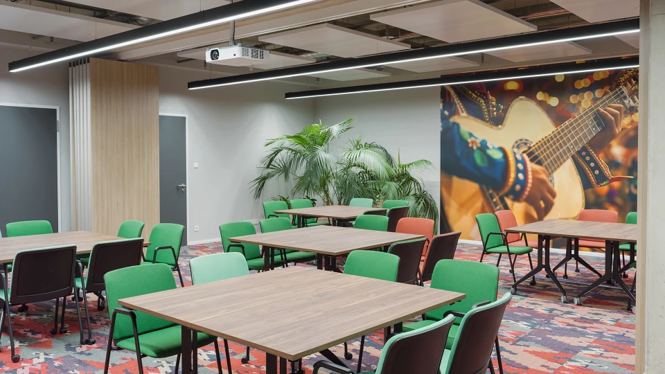 Blick auf die gegenüberliegende Raumhälfte „Kolumbien Cali“ mit Wandbild einer klassischen Gitarre, umgeben von satten Farben und tropischen Pflanzen.