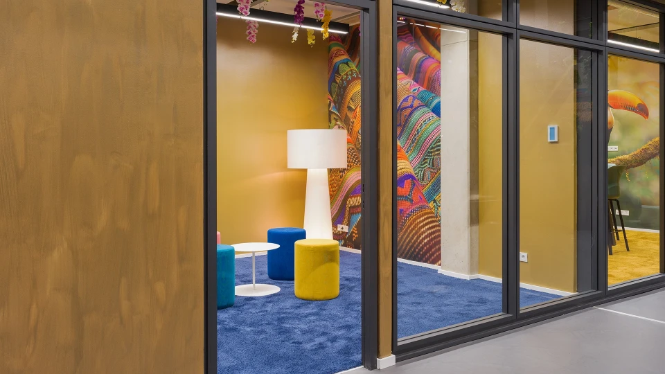 Exterior view of the 'Paraguay' room with a glass facade, showing stools, a floor lamp, and a flipchart.