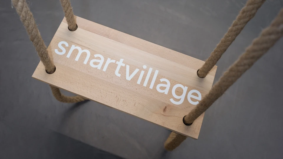 Close-up of a wooden swing with the inscription "smartvillage" on the seat.