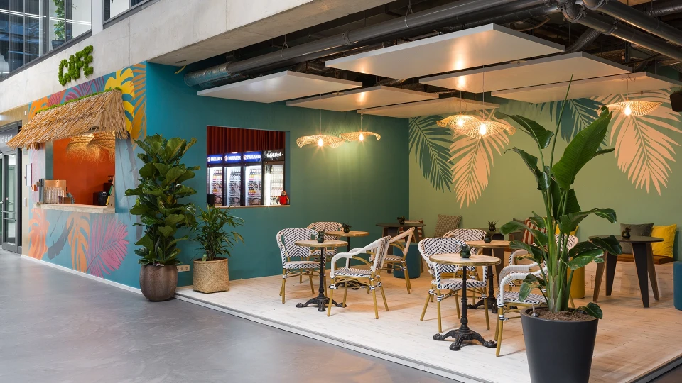 Front view of Smartcafé featuring circular café seating in front of a wall adorned with large palm motifs.