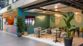 Front view of Smartcafé featuring circular café seating in front of a wall adorned with large palm motifs.