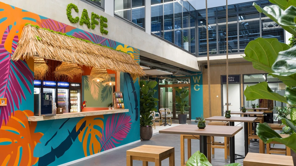 View of the counter at the Smartcafé featuring a thatched roof, colorful mural, and beverage coolers.