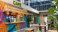 View of the counter at the Smartcafé featuring a thatched roof, colorful mural, and beverage coolers.