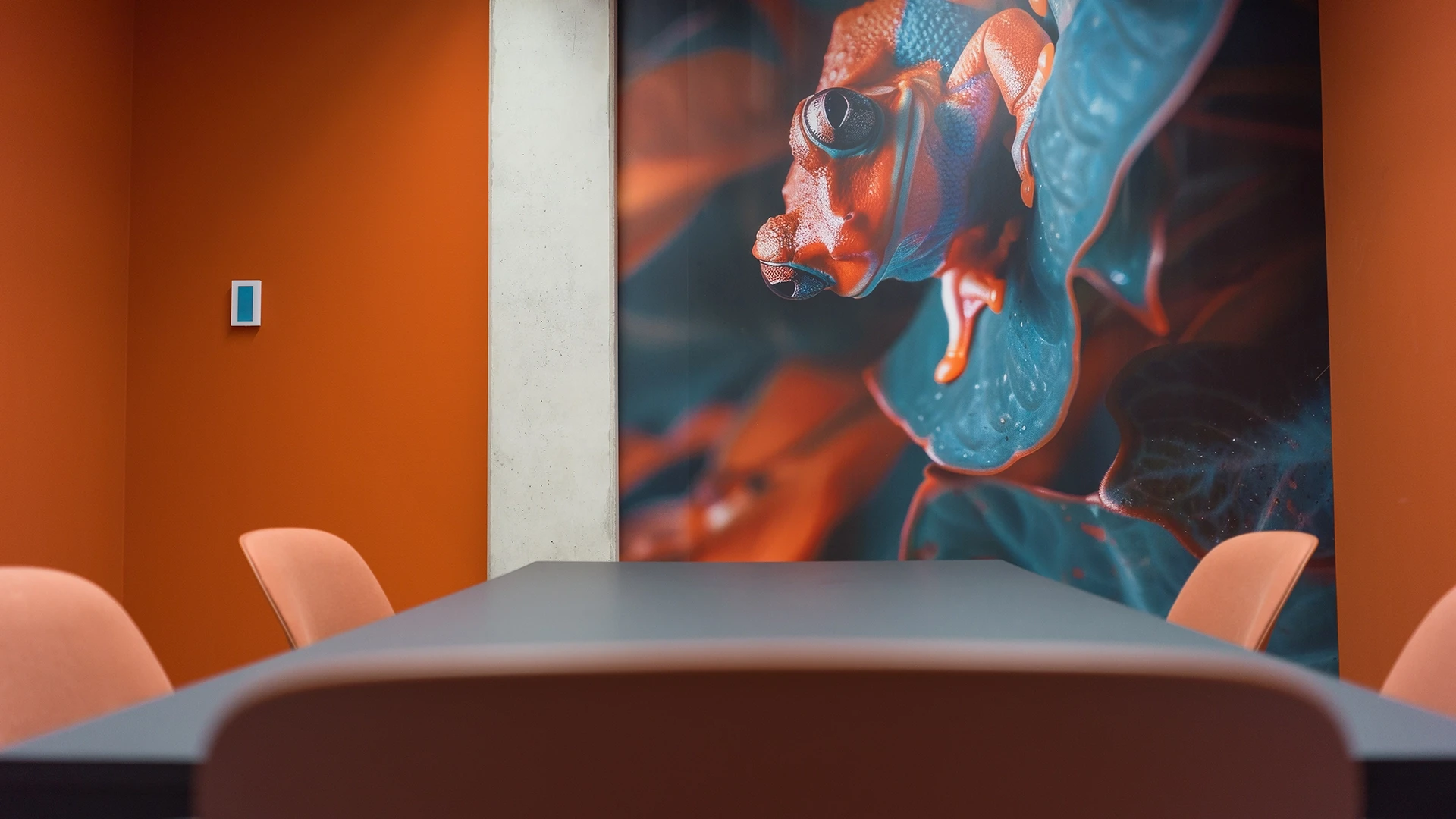 Side view of the meeting table in the 'Suriname' room, featuring a mural of a colorful frog on the wall.