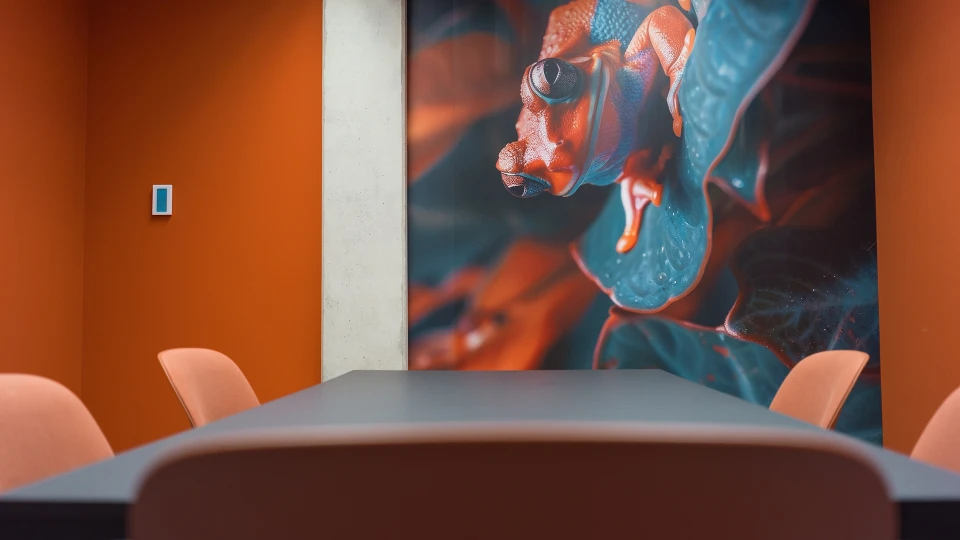 Side view of the meeting table in the 'Suriname' room, featuring a mural of a colorful frog on the wall.