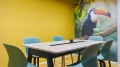 Bright meeting room with a yellow wall, light blue chairs, and a flipchart in smartvillage Cologne-Muelheim.
