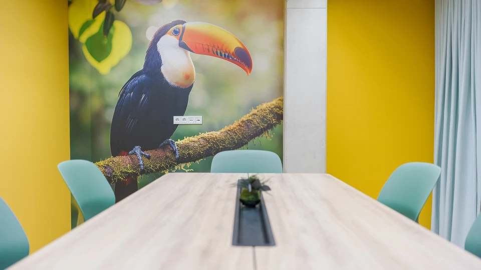 View through the windows of the 'Uruguay' room featuring modern tables and chairs at smartvillage Cologne-Mülheim.