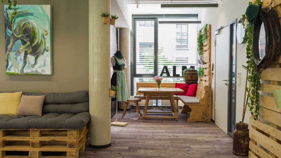 Cozy cafe interior with pallet sofas, wooden tables, hanging plants, and artistic decorations