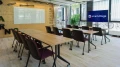Modern office conference room with long wooden table surrounded by red chairs, projector screen on wall, and 'smartvillage' company sign.