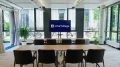 Conference room with a long wooden table and red chairs, a screen with the 'smartvillage' logo at the front, large windows in the background.