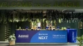 Empfangsbereich mit 'Welcome to the Jungle' Schild, verziert mit grünen Pflanzen, hinter einem Tresen mit 'Aareon NEXT' Banner.
