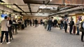 Mehrere Personen in einem großen, belebten Konferenzraum mit Ständen und Stehtischen, Gespräche führend und Informationsmaterial betrachtend.
