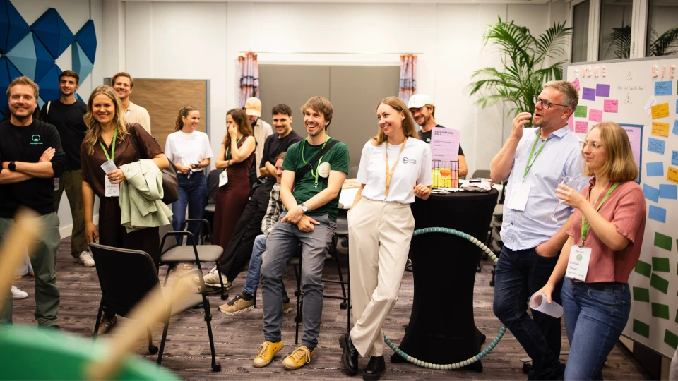 Gruppe von lächelnden Personen verschiedener Altersgruppen in einem Büro während eines Workshops mit Stühlen, Post-its und einem Flipchart